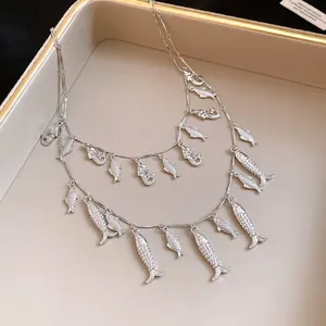 Détail du collier argenté double épaisseur avec plusieurs pendentifs poissons