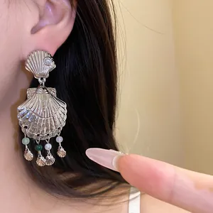 Primer plano de pendientes de borla de caracola plateada con cuentas de colores