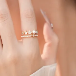 Close-up detail of a delicate gold ring set with heart zircons and elegant pearls