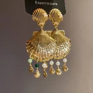 Vista detallada de elegantes pendientes de concha dorada con perlas y cuentas de colores