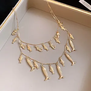 Gros plan sur un collier double rang doré vintage avec de petits pendentifs de poissons