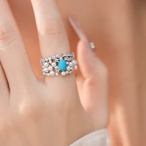 Macro view of exquisite court style ring featuring white pearls and oval turquoise stone on hand