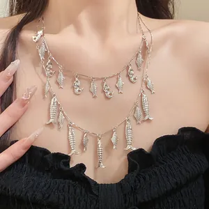 Vue détaillée d'un collier argenté à deux rangs avec des breloques de poisson sur un modèle.