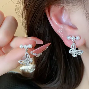 Detailed view of dainty silver butterfly pearl stud earrings with sparkling crystals.