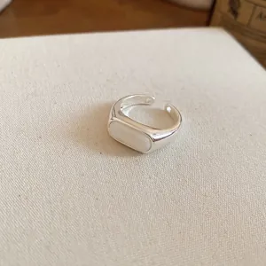 Close-up detail of a minimalist silver open ring featuring an elegant white resin oval inlay