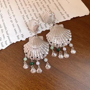 Primer plano de pendientes de concha plateada con elegantes cuentas verdes y blancas