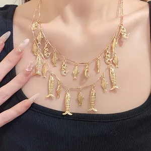 Détail d'un collier double rang doré orné de plusieurs pendentifs en forme de poisson