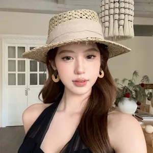 Gros plan d'un mannequin portant des créoles en rotin tressé et un chapeau de paille assorti