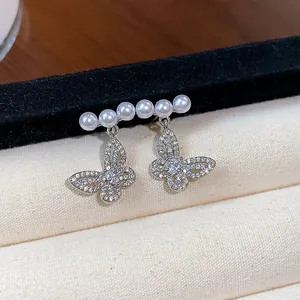 Exquisite close-up showing hollow butterfly stud earrings with delicate small pearls