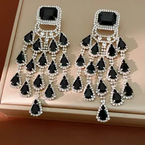 Detailed macro view of exaggerated black teardrop tassel earrings with sparkling rhinestones