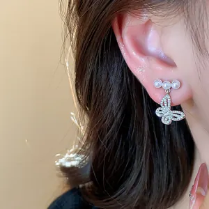 Detailed close-up showing elegant butterfly pearl stud earrings worn on a lady's ear.