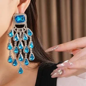 Glamorous blue teardrop tassel earrings with silver needles and rhinestones worn on ear