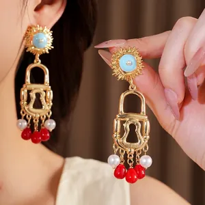 Exaggerated vintage golden lock earrings with blue sun motif and red acrylic pearl tassels