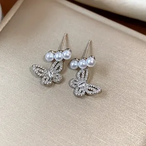 Close-up of elegant hollow butterfly earrings with sparkling stones and pearls