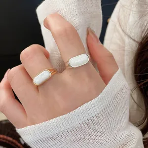 Close-up of 18k gold plated open rings with white resin inlay on fingers