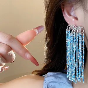 Close-up of blue and white beaded tassel earrings worn on ear with natural sunlight