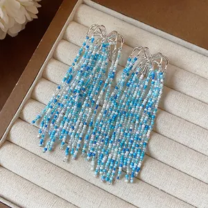 Macro view of elegant blue and white firework style glass bead tassel earrings.