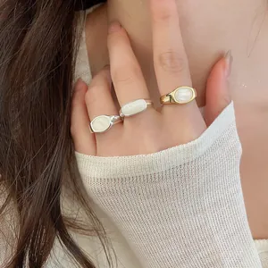 Detailed view of minimalist resin stone rings with gold and silver finishes on a hand