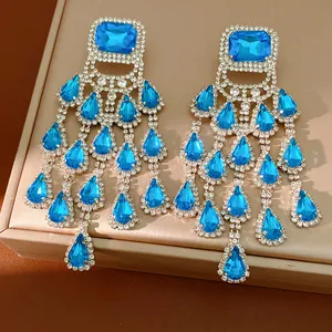 Detailed close-up of blue crystal teardrop tassel earrings on a luxury jewelry box.