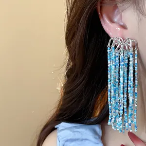 Detailed close-up shot of elegant blue glass bead tassel earrings on a model's ear
