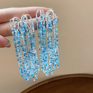 Close-up of blue glass bead tassel earrings showing intricate fringe detail and metal hooks