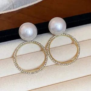 Elegantes pendientes de aro dorados con perlas grandes e incrustaciones de cristales.