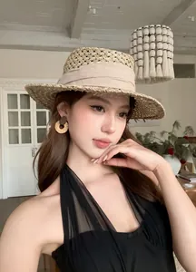 Détail des boucles d'oreilles créoles tressées portées avec un chapeau de paille