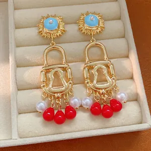 Detail view of ornate gold lock-shaped earrings with blue accents and colorful charms