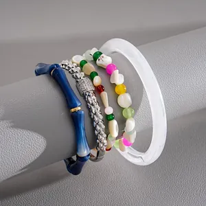 Dettaglio di braccialetti con perline colorate e gioielli elastici in stile bambù.