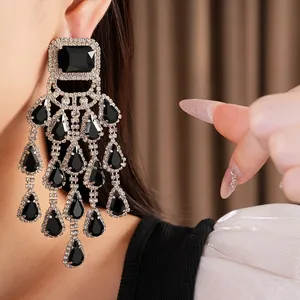 Close-up of exaggerated black teardrop tassel earrings with sparkling rhinestones on model