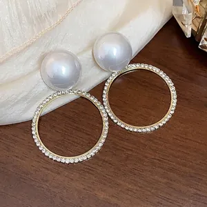 Elegantes pendientes de aro dorados con perlas blancas y adornos de pedrería.