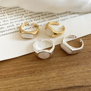 Close-up detail of 18k gold plated open rings featuring elegant white resin oval inlays