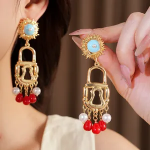 Detailed close-up of gold-tone lock earrings with blue accents and red teardrop tassels.