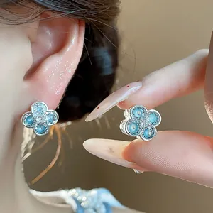 Detailed close-up of light blue dripping oil flower earrings with sparkling zircon center
