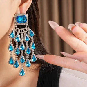 Close-up view of elegant blue rhinestone chandelier fringe earrings worn by a model
