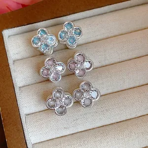 Close-up of three pairs of zircon four-leaf clover earrings in blue, pink, and white