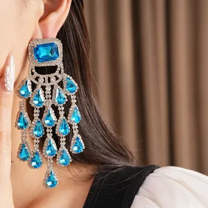 Close-up of exaggerated chandelier earring with blue water drop tassels and rhinestones
