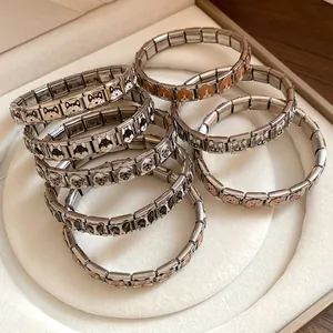 Close-up detail showing various stainless steel dog charm bracelets with colorful enamel