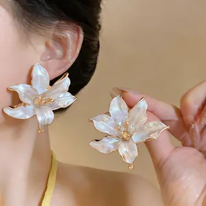 Dettaglio ravvicinato di eleganti orecchini a fiore bianco e oro sul modello