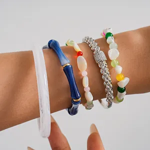 Dettaglio ravvicinato di bracciali in bambù acrilico e perline colorate impilati sul polso