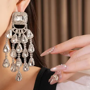 Detailed close-up of luxurious sparkling rhinestone teardrop tassel chandelier earrings on a model