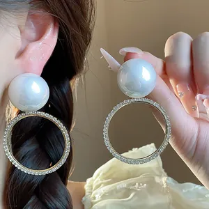 Primer plano de elegantes pendientes de perlas con aros dorados incrustados de cristales.