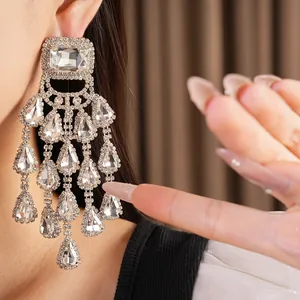 Close-up detail of sparkling silver tassel earrings featuring square and teardrop stones.