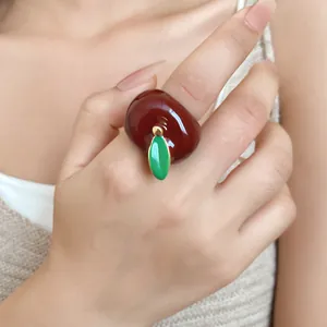 Primer plano de un anillo de manzana de esmalte rojo brillante con una hoja verde.