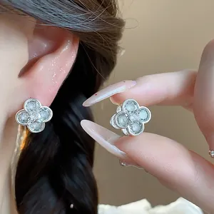 Close-up of delicate silver flower hoop earrings with zircon stones and beaded edges.