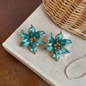 Dettaglio di eleganti orecchini a perno a fiore blu con accenti dorati su un libro