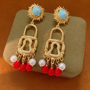 Detailed view of vintage gold lock earrings featuring red tassels and white pearl accents