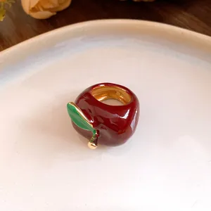 Detalle de un encantador anillo de manzana en esmalte rojo con banda dorada y hoja