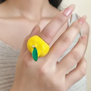 Detalle de un anillo de manzana amarilla vibrante con esmalte de aceite en el dedo