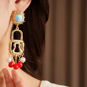 Macro detail shot of vintage gold lock earrings with pearls and red beads fringe charms.
